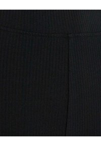 Leggings noirs à côtes avec une finition texturée. Dotés d'une taille haute et d'un design sans coutures, offrant une apparence ajustée.