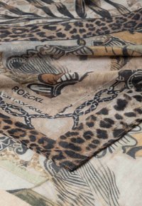 Leopard print scarf with a soft texture. Features intricate patterns in brown, beige, and black hues, complemented by a tribal design.