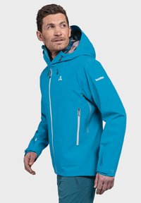 Helle blaue wasserdichte Jacke mit Kapuze, Reißverschluss vorne und Taschen, mit einem weißen Logo auf dem linken Ärmel und verstellbaren Bündchen.