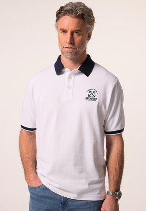 Weißes Poloshirt mit einem marineblauen Kragen und marineblauen Akzenten an den Ärmeln. Verfügt über gestickten Text und ein Design mit gekreuzten Ankern.