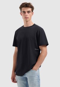 Zwart t-shirt met korte mouwen en een ronde hals, gemaakt van stevige stof. Heeft een klein wit tekstdetail aan de linkerkant. Casual pasvorm.
