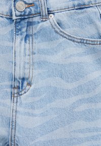 Jean en denim bleu clair avec un motif ondulé subtil, des surpiqûres contrastantes, une fermeture par bouton métallique et un design à cinq poches.