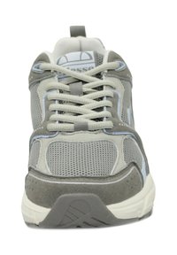 Scarpa atletica grigia realizzata in materiali in rete e suede. Presenta stringhe prominenti, dettagli azzurri chiari e una suola testurizzata. Vista frontale.