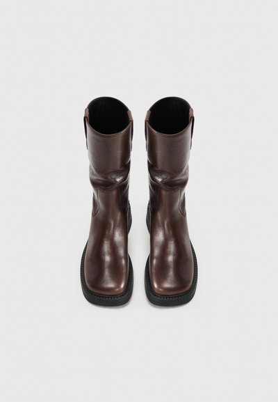 Brown leather ankle boots with a smooth finish, square toe, and low rubber sole. Features pull tabs on the shaft for easy wear.