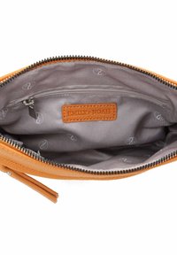 Interno di una borsa in pelle arancione con una fodera grigia, dotato di una tasca con zip e di un etichetta in pelle cucita. Interno in tessuto con motivo discreto.