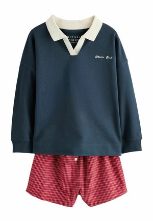 Tricou polo bleumarin cu mânecă lungă, guler alb și textul „Athletic Club”, asortat cu pantaloni scurți roșii în carouri.