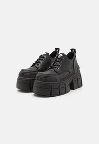 Platform shoes made of black leather with thick rubber soles. Features lace-up design, padded collar, and logo on the side.