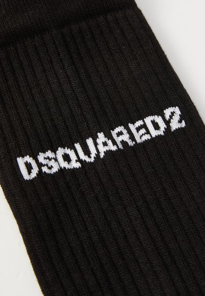 Sort ribbet stof med hvid strikket tekst "DSQUARED2" vandret hen over overfladen.