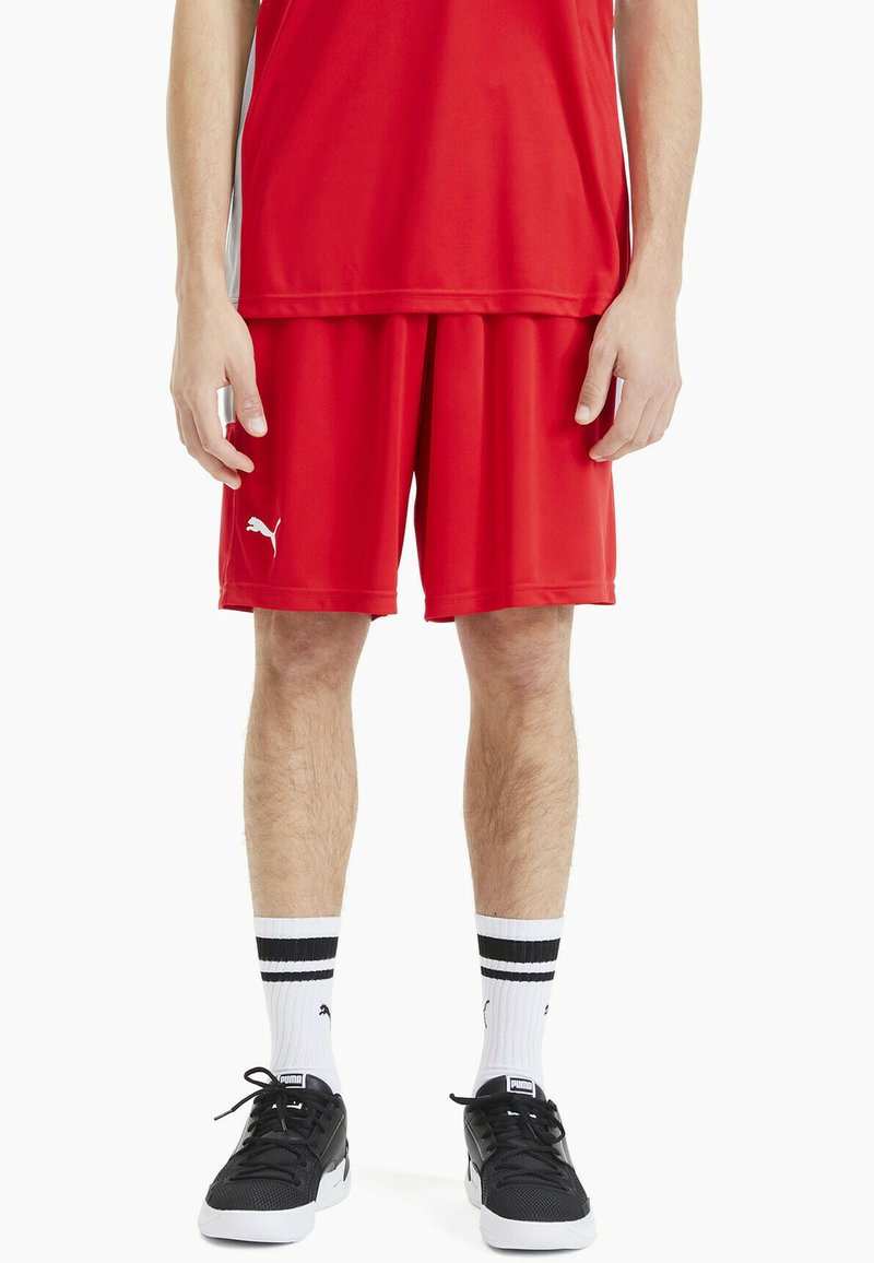Rotes Sporttrikot und Shorts aus atmungsaktivem Material, kombiniert mit schwarzen Sneakern und weißen Socken mit schwarzen Streifen. Puma-Logo sichtbar.