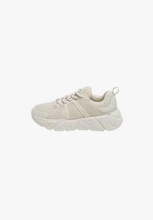 Beige sneaker with a mesh upper, textured accents, and a thick sole. Features prominent branding on the side and a pull tab at the heel.