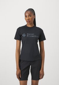 Svart kortermet skjorte med rund hals og subtil tekstur. Har en refleksiv "Sweet Protection" logo foran.