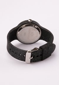 Reloj negro con una correa texturizada que presenta un patrón moteado. Parte trasera de metal con marca; resistente al agua con un detalle de hebilla plateada.