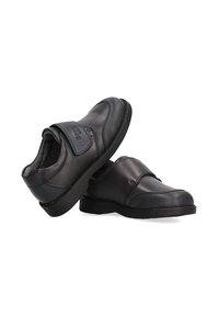 Zapatos de cuero negros con un acabado suave y acentos texturizados. Presentan una correa de Velcro y una punta redonda, con una suela de goma.