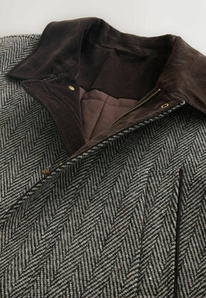 Villakangastakki herringbone-kuviolla, jossa on ruskea samettikaulus, kultaiset yksityiskohdat ja vetoketjusuljenta. Rakenteellinen harmaa ja musta kangas, jossa on sileä sisävuori.