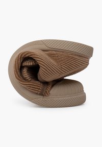 Des chaussures marron avec un intérieur doux et côtelé et une semelle en caoutchouc texturé, conçues pour être flexibles et facilement compressibles.