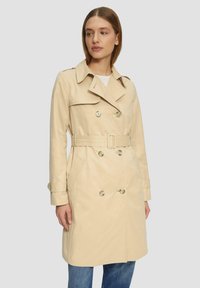 Beige trenchcoat met een dubbelzijdig ontwerp, een ceintuur in de taille, een grote kraag en knopaankleding. Voorzien van zijvakjes en gestructureerde manchetten.