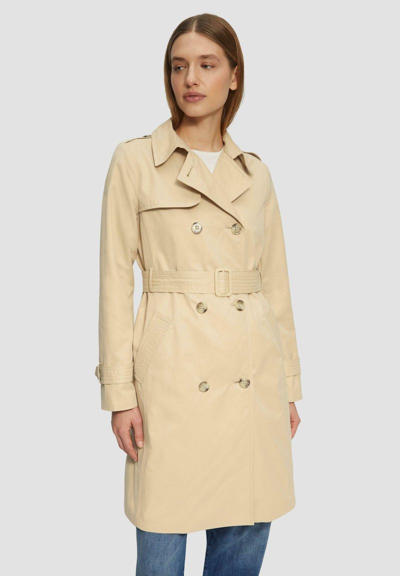 Beige trenchcoat met een dubbelzijdig ontwerp, een ceintuur in de taille, een grote kraag en knopaankleding. Voorzien van zijvakjes en gestructureerde manchetten.