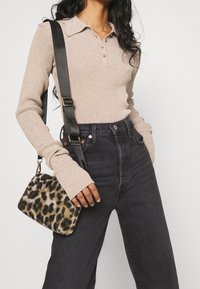 Beige ribbad långärmad topp med krage, mörka högmidjade jeans och en liten väska i leopardmönster med rem och guldutrustning.