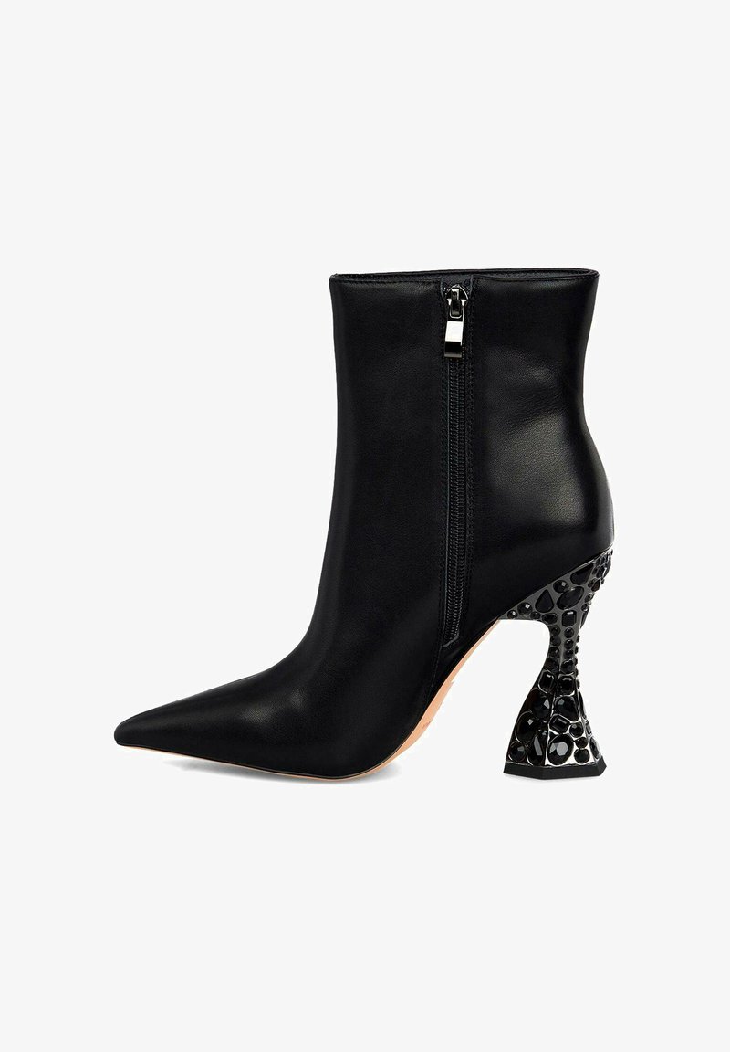 Bottine en cuir noir avec un bout pointu, fermeture à glissière, et un talon noir orné et sculptural présentant un motif géométrique.