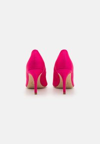 Pink high-heeled shoes with a smooth fabric texture, pointed toe, and narrow heels. The design features minimalistic lines and no visible accents.