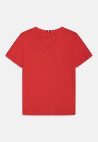 T-shirt corto a maniche corte in cotone rosso con scollatura a V e orlo dritto. Il retro presenta una striscia verticale a contrasto all'altezza del colletto.