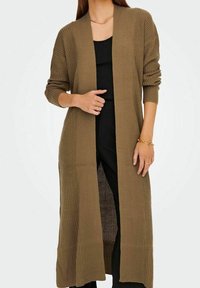 Cardigan long à devant ouvert en maille texturée vert olive, avec un design côtelé et des manches longues, porté sur un ensemble noir.