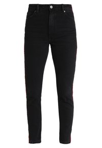 Černé riflové kalhoty s vysokým pasem a slim fit. Mají červené boční pruhy. Vyrobeny z denimu s hladkou texturou a tradičním designem pěti kapes.