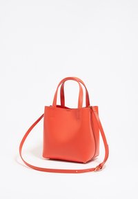 Czerwona skórzana torba typu tote z dwoma krótkimi uchwytami i regulowanym długim paskiem. Gładka tekstura i minimalistyczny design bez widocznego osprzętu.