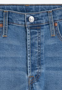 Jeans in denim blu con una trama liscia, bottone in metallo rame e cuciture arancioni lungo le cuciture, con un classico design a cinque tasche.