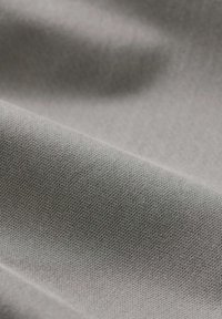 Tessuto grigio con una superficie liscia e strutturata, che mostra un sottile motivo di intreccio. Il colore è uniforme, con la luce che si riflette sulla superficie.
