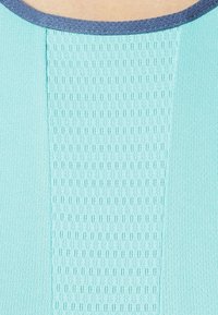 Lichtblauw topje met een getextureerd, geperforeerd middenpaneel. Gladde randen met een contrasterende donkerblauwe rand. Zachte stofafwerking.