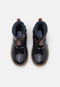 Černé lakované kotníkové boty s měkkým modrým podšívkou, třpytivými akcenty a detailem řas na přední straně. Boční zip pro snadné oblékání.