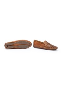 Chaussures à enfiler en cuir marron avec un motif floral découpé au laser à l'avant, semelle en caoutchouc avec grip circulaire et détails de couture visibles le long du bord.