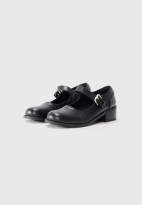 Black leather Mary Jane shoes with a rounded toe, perforated detailing, and a buckle strap. Low heel and smooth texture.