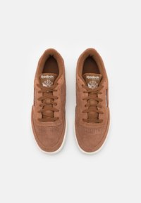 Baskets en daim marron à design basse, dotées de lacets ronds, d'un bout perforé et d'une semelle en caoutchouc blanche. Logo Reebok sur la languette.