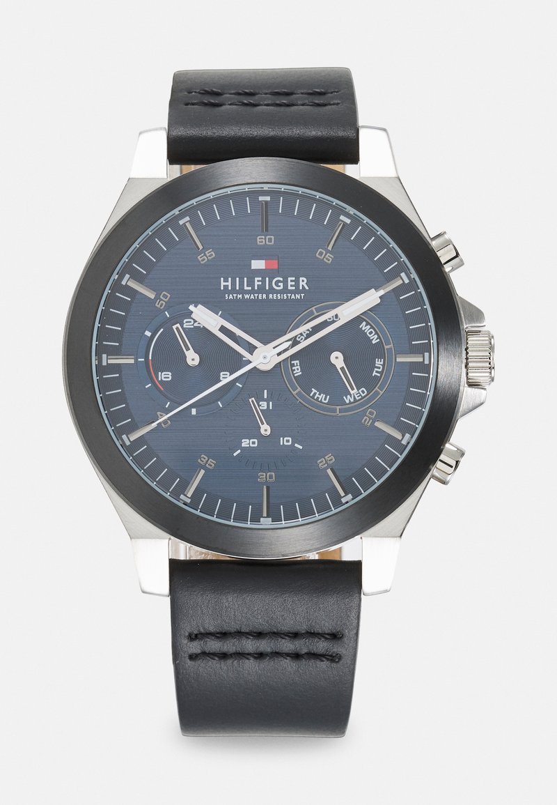 Reloj de acero inoxidable con forma redonda, dial texturizado en azul oscuro, marcadores de hora en blanco y correa de cuero negra. Presenta tres sub-diales y cronógrafo.