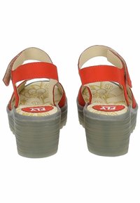 Rode leren sandalen met verstelbare achterbanden, verhoogde grijze platformzool met textuur, en een gepatteerde binnenzool met bloemendessin.