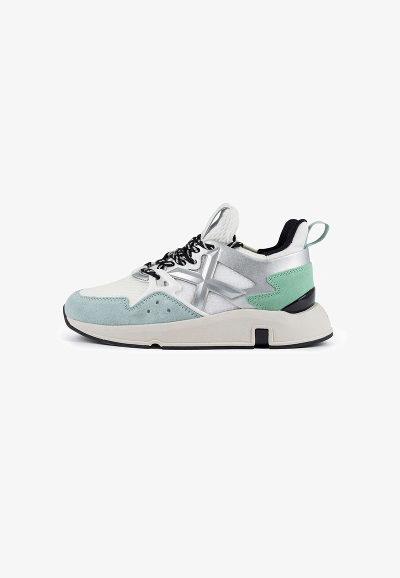 Sneaker mit einem weißen Mesh-Obermaterial, mintgrünen Wildlederakzenten, silbernen Details, schwarzen Schnürsenkeln und einer dicken weißen Sohle mit schwarzem Profil.