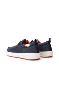 Navy canvas shoes with white soles, featuring orange accents, lace detailing, and a pull tab on the heel for easy wear.