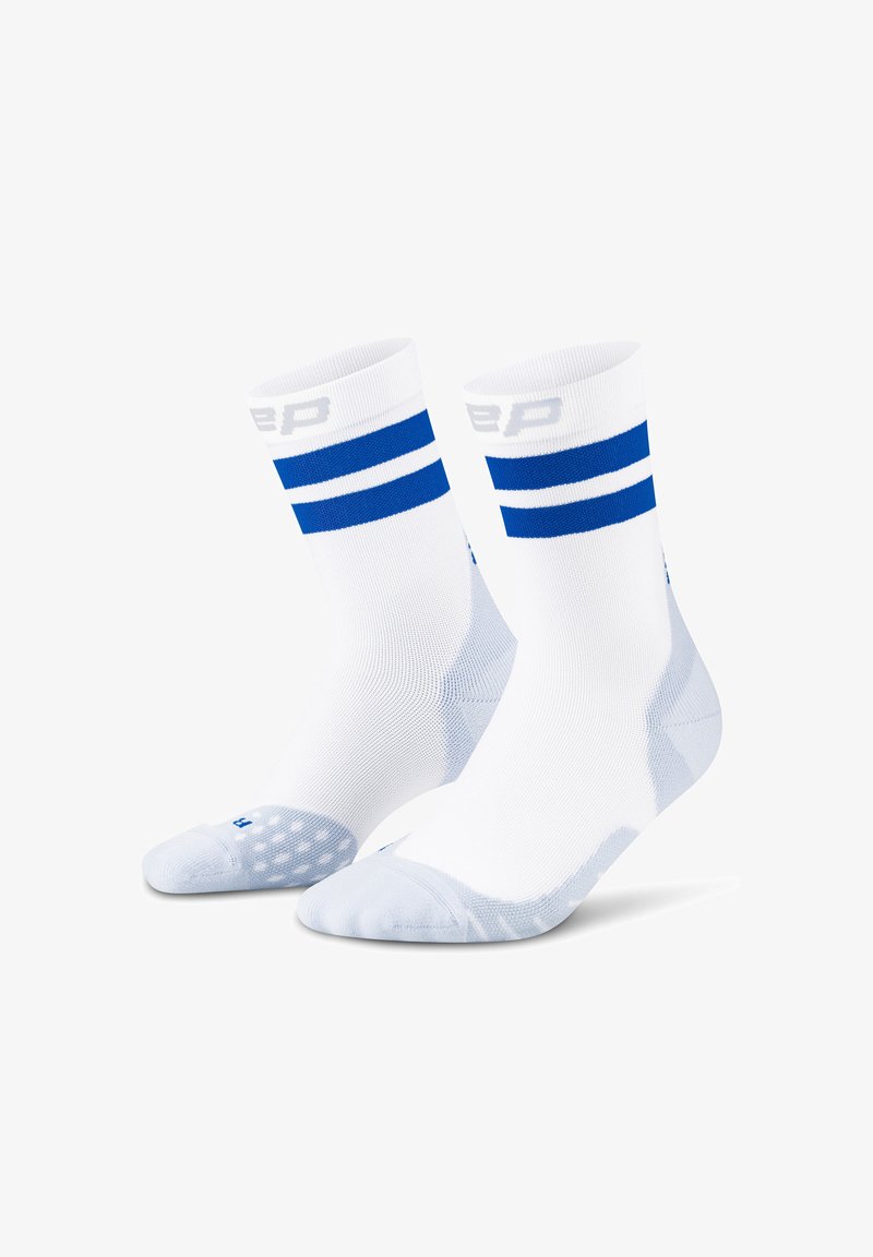 Un paio di calzini sportivi bianchi con doppie strisce blu nella parte superiore e suole imbottite, in posizione verticale su uno sfondo bianco.
