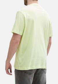 T-shirt en coton jaune clair avec des manches courtes et un col rond, présenté de dos. Texture lisse, coupe décontractée.