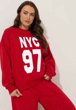 Sudadera roja de gran tamaño hecha de algodón con impresión blanca "NYC 97". Cuenta con puños y dobladillo acanalados, ajuste holgado, combinada con pantalones a juego.