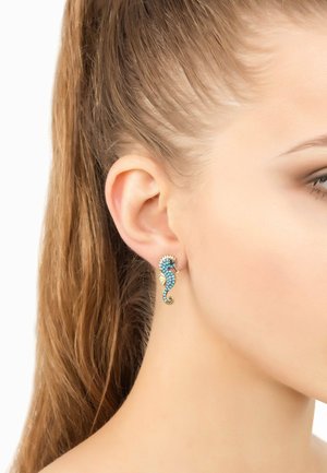 Orecchino a forma di cavalluccio marino con rhinestones aquamarina e blu su una base in metallo dorato. Design della coda intricato e pinne texturizzate.