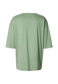 Tričko s krátkým rukávem, volného střihu, vyrobené z lehké zelené bavlny. Má kulatý výstřih a bezšvová ramena s hladkým povrchem.