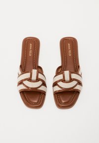 Brune læderslidesandaler med en bred beige stofrem, der har et flettet design. Syningsdetaljer på sålen. Uden hæl.