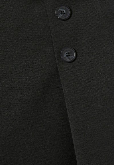 Tela negra de textura suave con dos botones negros. Un diseño entallado que enfatiza un aspecto estructurado pero clásico.