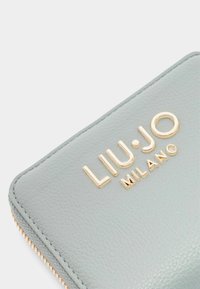 Lichtgrijze leren portemonnee met een goudkleurig logo "LIU•JO MILANO" en een gestructureerd oppervlak, met een contrasterende gestikte ritsrand.