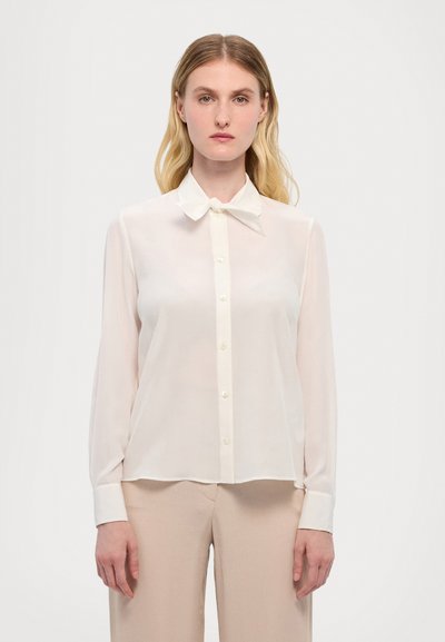 Weiße, durchsichtige Bluse mit einer Schleifenkragen, langen Ärmeln und Knopfverschluss. Sie hat eine glatte Textur und ein lockeres, fließendes Design.