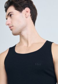 Schwarzes Tanktop aus geripptem Stoff, mit einem runden Ausschnitt und dezent gesticktem "BOSS"-Logo auf der Brust.
