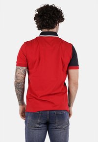 Polo a maniche corte rosso e nero con colletto a contrasto, caratterizzato da una texture liscia e un accento ricamato sulla manica.